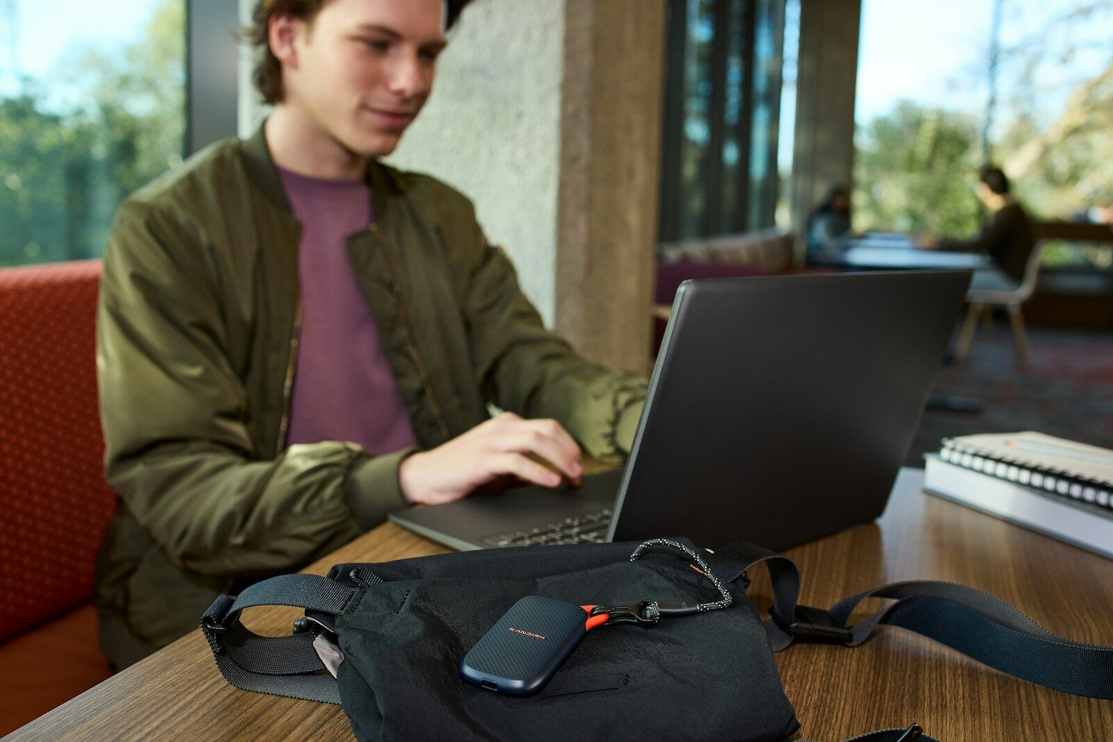 Young man uses laptop, portable storage device on table
